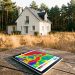 Maison individuelle française située en lisière de forêt, avec une tablette affichant une carte abstraite du risque d’incendie, entourée de végétation sèche sous une lumière estivale.